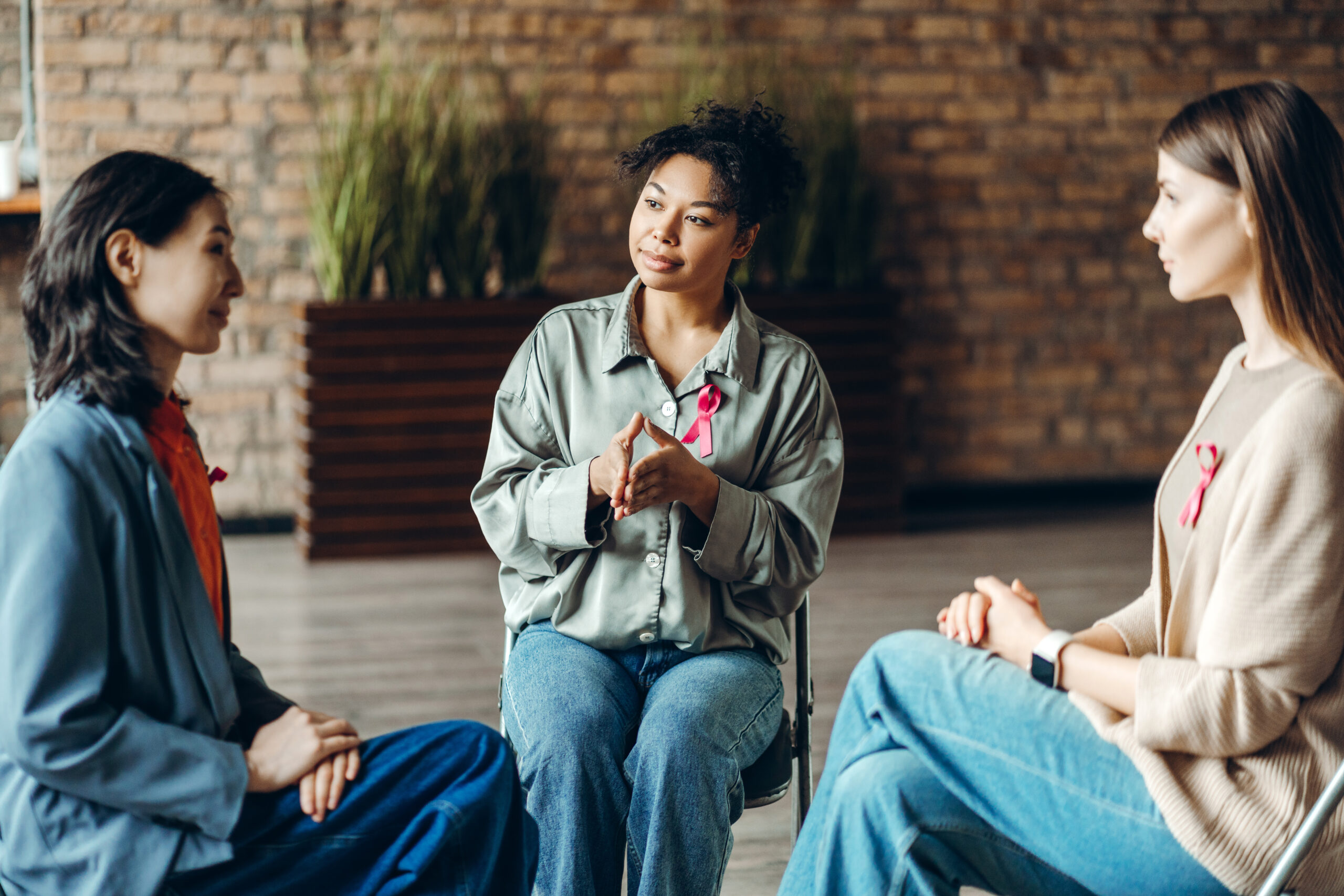 Group of multiracial women supporting each other during breast cancer awareness month meeting