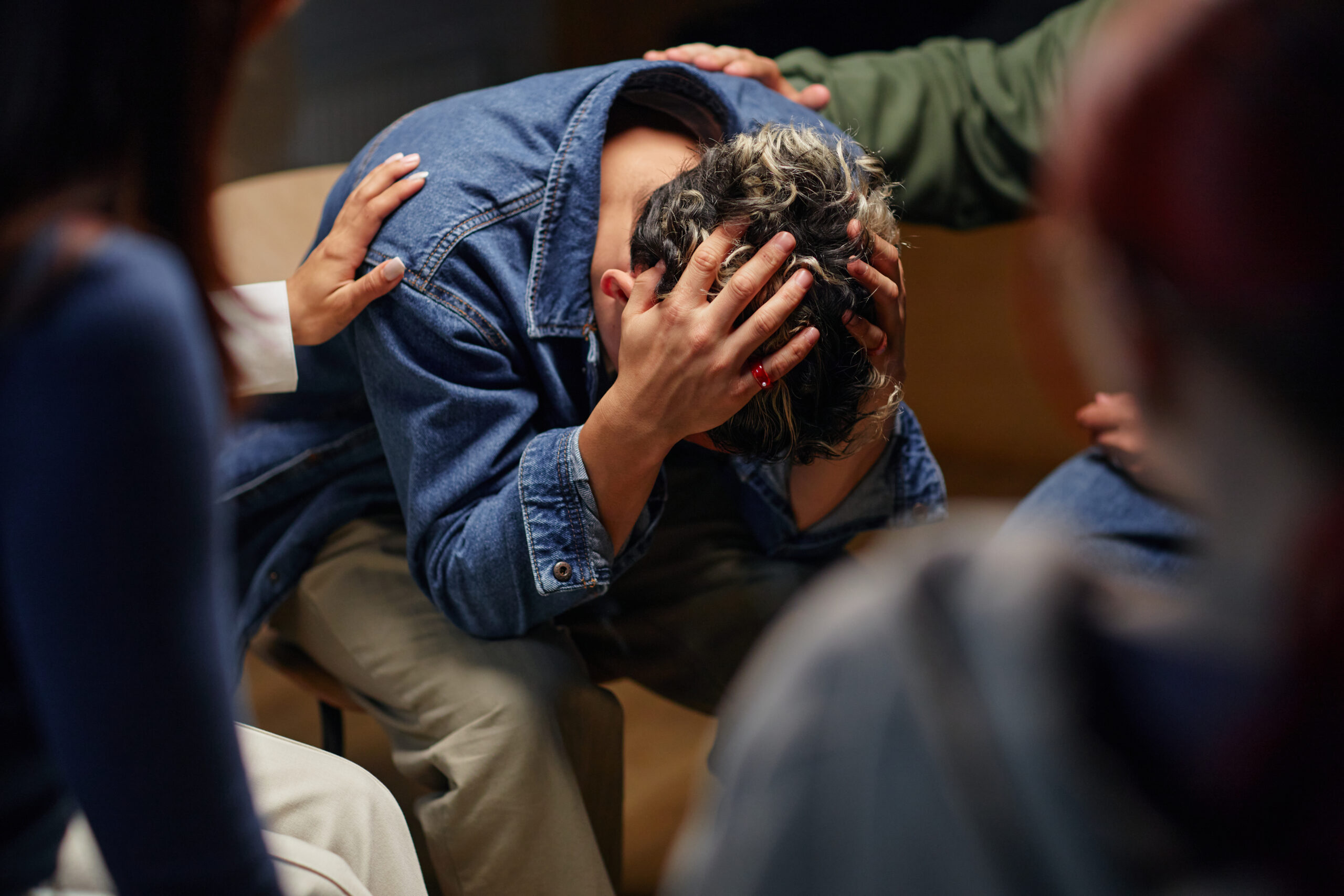 Teenage Boy Sitting with Head in Hands Receiving Group Support